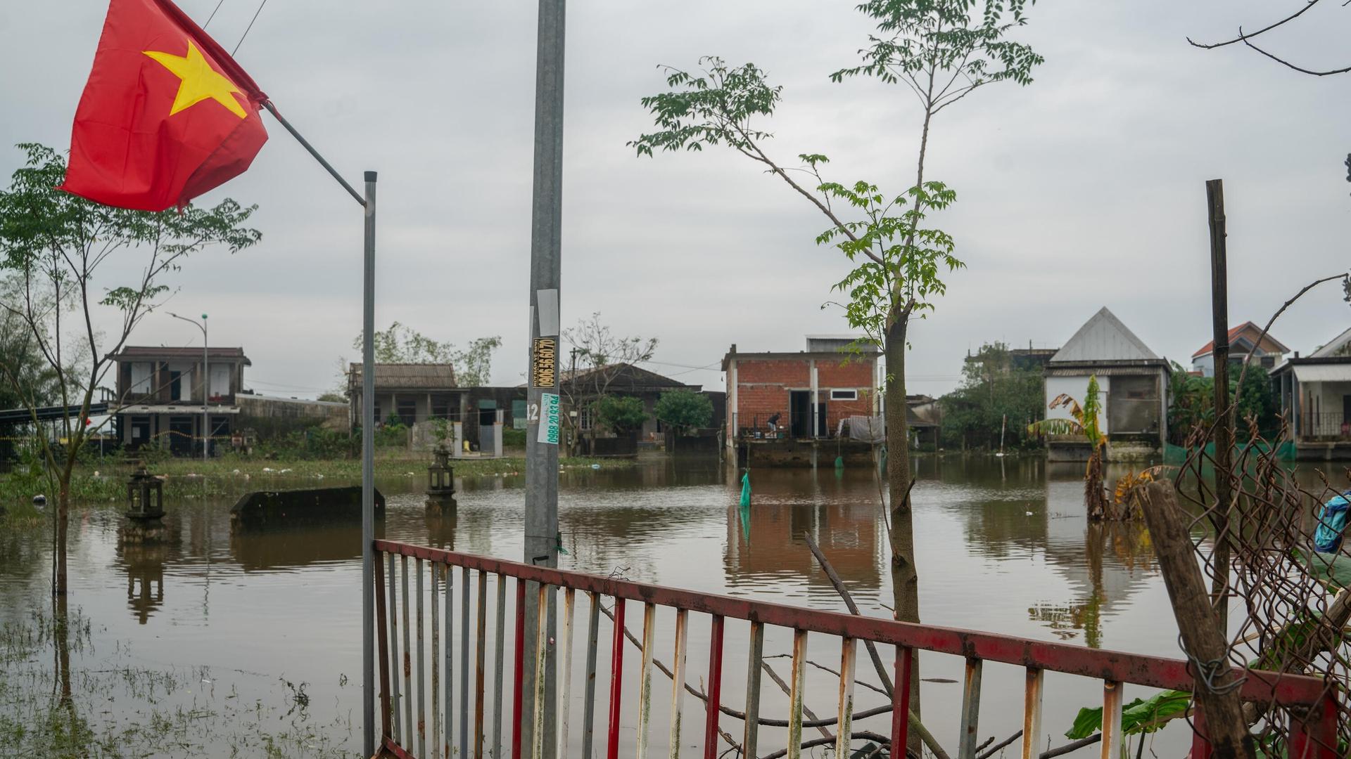 Überschwemmung in Vietnam: Abgebildet ist eine Landesflagge sowie mehrere betroffene Gebäude.