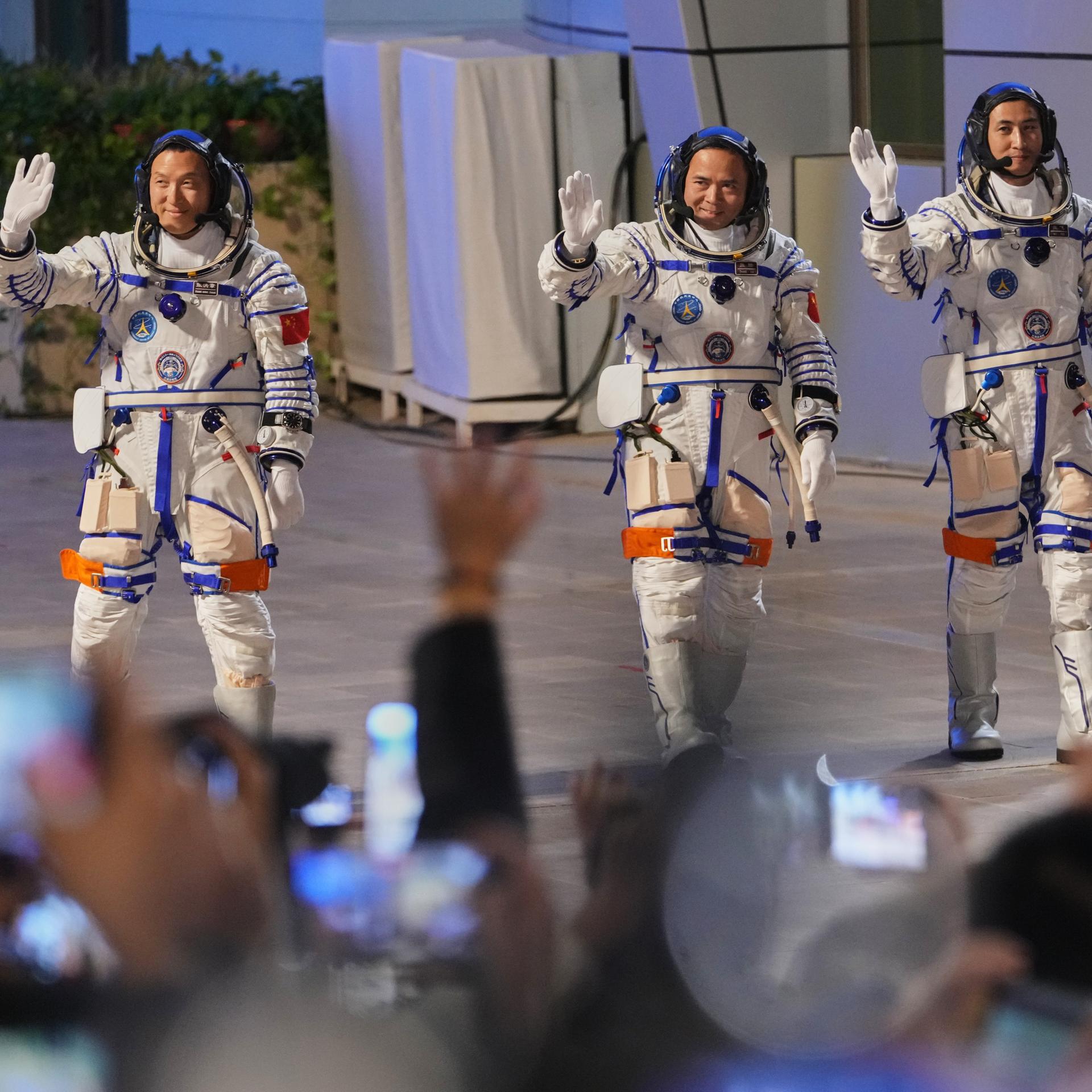 Die chinesischen Astronauten der Mission Shenzhou 21 Zhang Hongzhang (l-r), Zhang Lu und Wu Fei, winken bei der Abschiedszeremonie für ihre bemannte Raumfahrtmission im Jiuquan Satellite Launch Center.