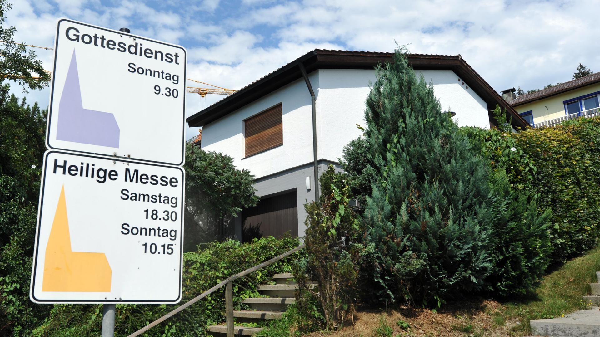 An einem Haus in Leutkirch (Kreis Ravensburg) sind die Rollläden heruntergelassen. Vor dem Haus zwei Schilder mit Hinweise auf den Gottesdienst und die Heilige Messe