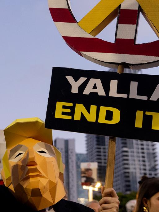Ein Demonstrant trägt ein Kostüm von US-Präsident Donald Trump während eines Marsches in Tel Aviv und hält ein Schild mit der Aufschrift "Yalla - End it!"