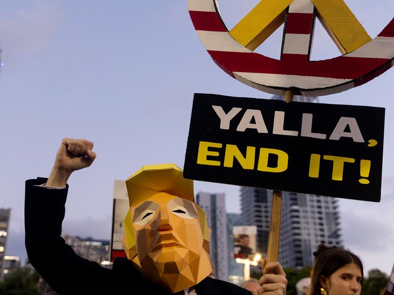 Ein Demonstrant trägt ein Kostüm von US-Präsident Donald Trump während eines Marsches in Tel Aviv und hält ein Schild mit der Aufschrift "Yalla - End it!"