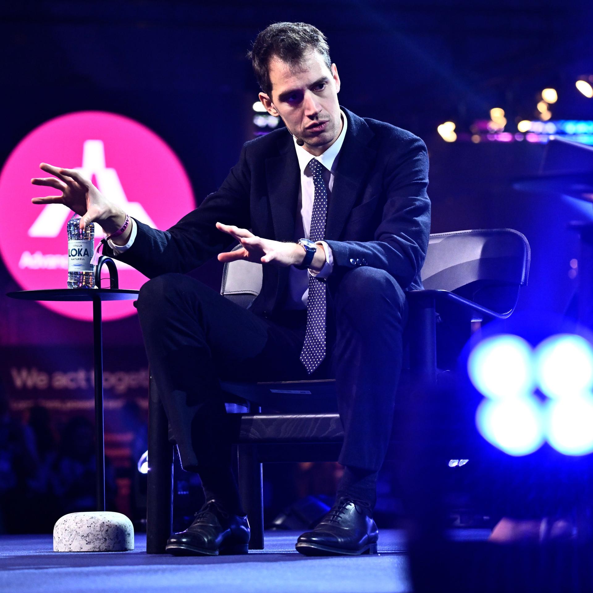 Der Mitgründer des französischen KI-Unternehmens Mistral AI, Arthur Mensch, sitzt bei einem Interview und gestikuliert mit beiden Händen.