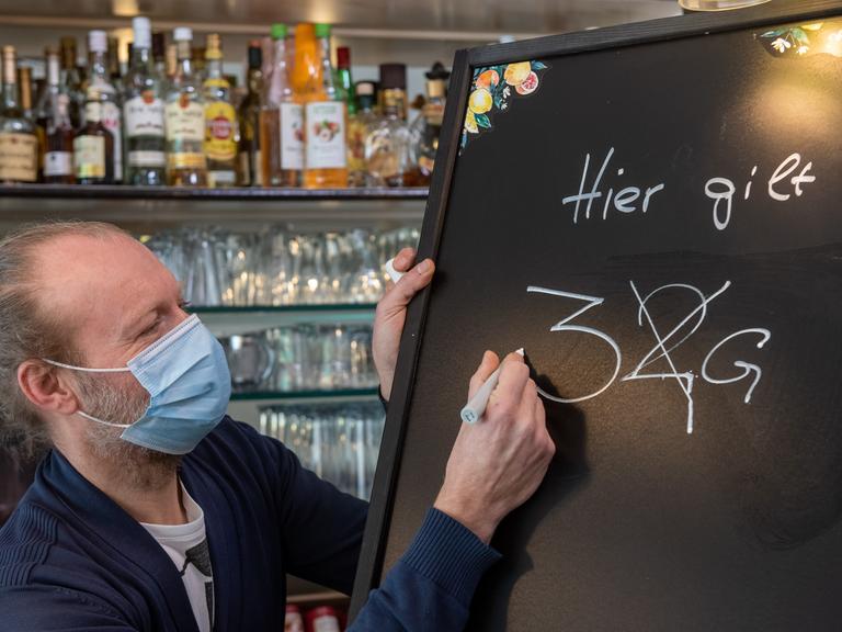 

Gastronom Jörg Hicker passt eine Informationstafel an. Ab dem 04.03.2022 gilt in der bayerischen Gastronomie die 3G-Regel.
