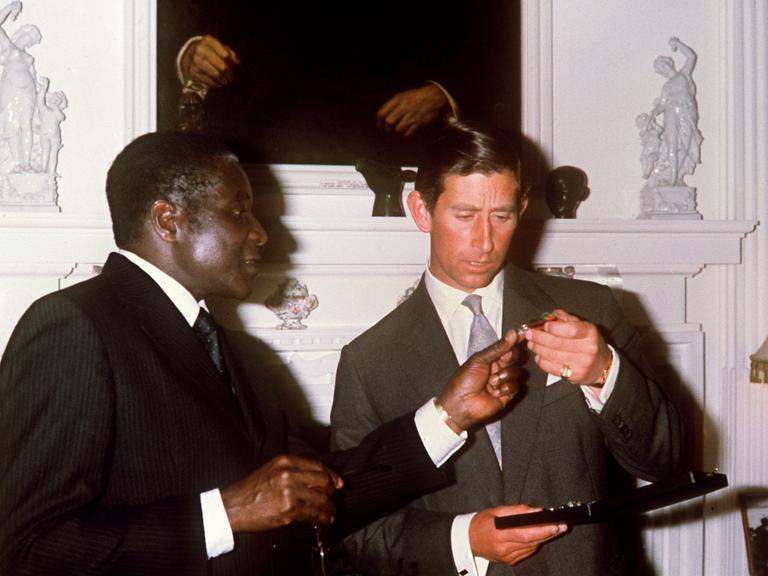 Robert Mugabe  überreicht im Rahmen eines feierlichen Abendessens im Regierungssitz in Salisbury Mitte April 1980 dem britischen Thronfolger Prinz Charles eine Unabhängigkeitsmedaille. Die ehemalige britische Kolonie Rhodesien wurde nach den Wahlen im Februar 1980 am 18.4.1980 unter dem Namen Simbabwe unabhängig. Erster Premierminister des neuen Landes wurde im März 1980 Robert Mugabe. Prinz Charles nahm an den Feierlichkeiten zur Unabhängigkeit teil.