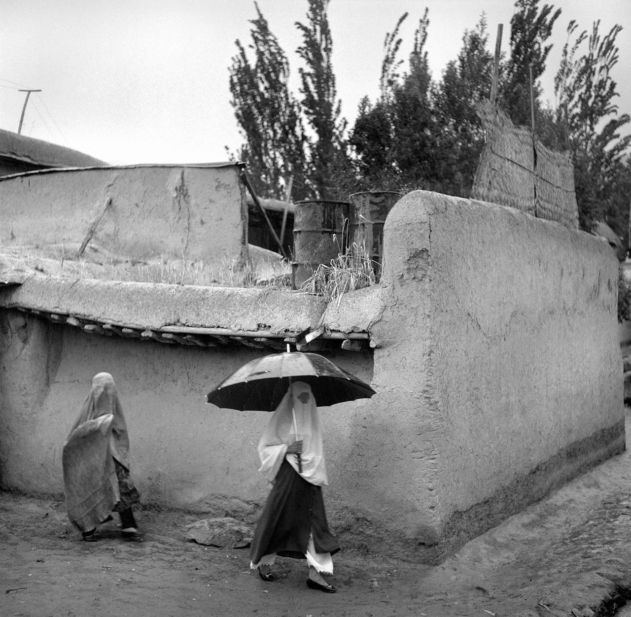 Afghanische Frauen mit einem Regenschirm, auf dem Weg zum Markt. Sie tragen Vollverschleierung, eine Burka. Badakhshan Provinz, 2001.