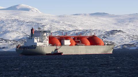 Ein Schiff zur Erdgasförderung fährt vor einer verschneiten Berglandschaft entlang.