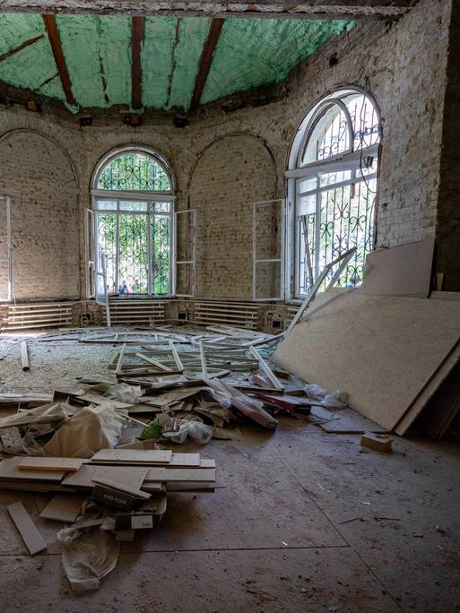 Ein Raum des zerstörten Kinderkrankenhauses in Kiew: die Fenster sind beschädigt, überall liegen Steine und Schutt herum.