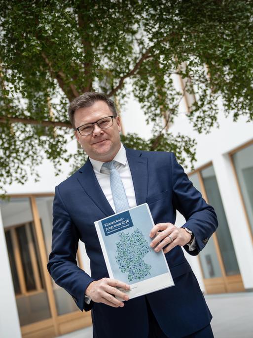 Umweltminister Carsten Schneider steht vor einem Baum und präsentiert eine Broschüre. Umweltminister Carsten Schneider steht vor einem Baum und präsentiert eine Broschüre.