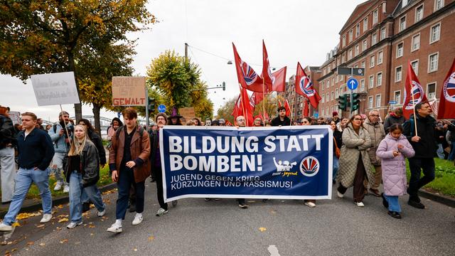 Demonstranten gehen bei einer Kundgebung hinter einem Transparent mit dem Aufdruck "Bild statt Bomben!".