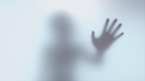Der Schatten einer Hand hinter einer Milchglasscheibe