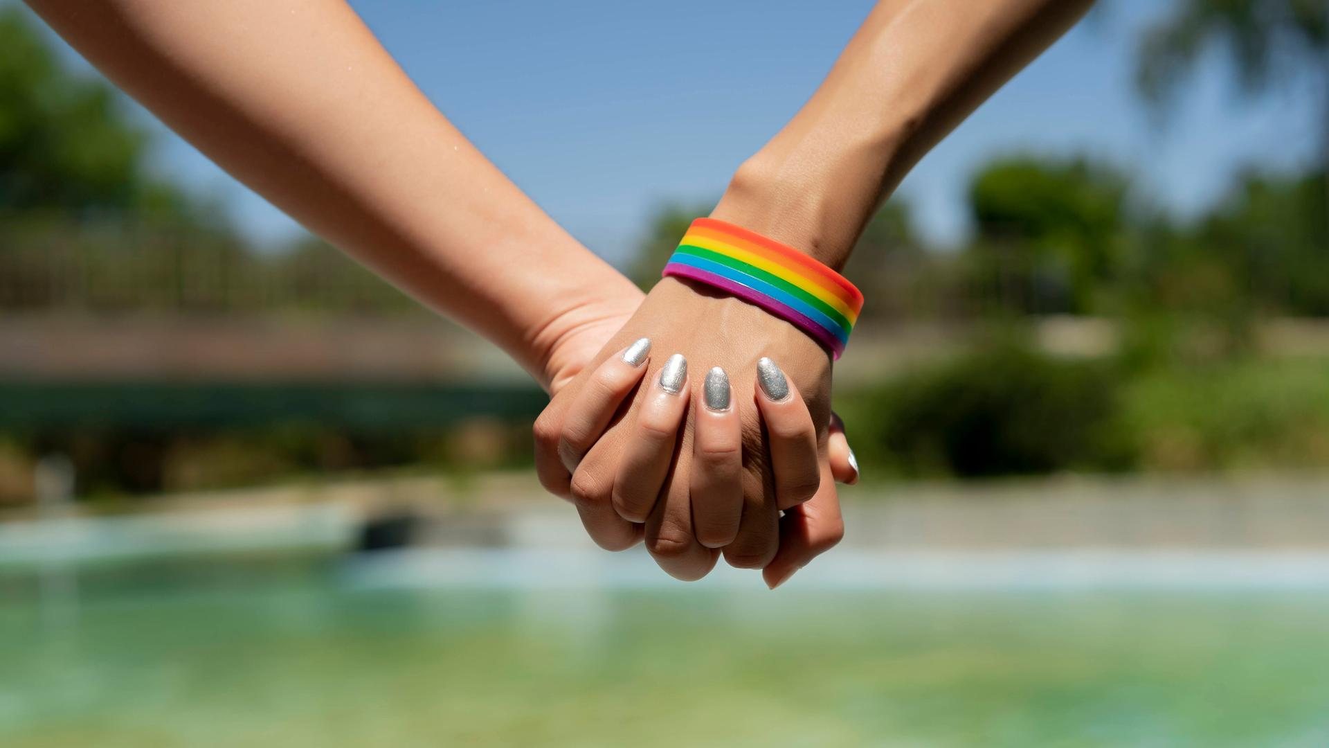 Zwei queere Frauen halten sich an der Hand.