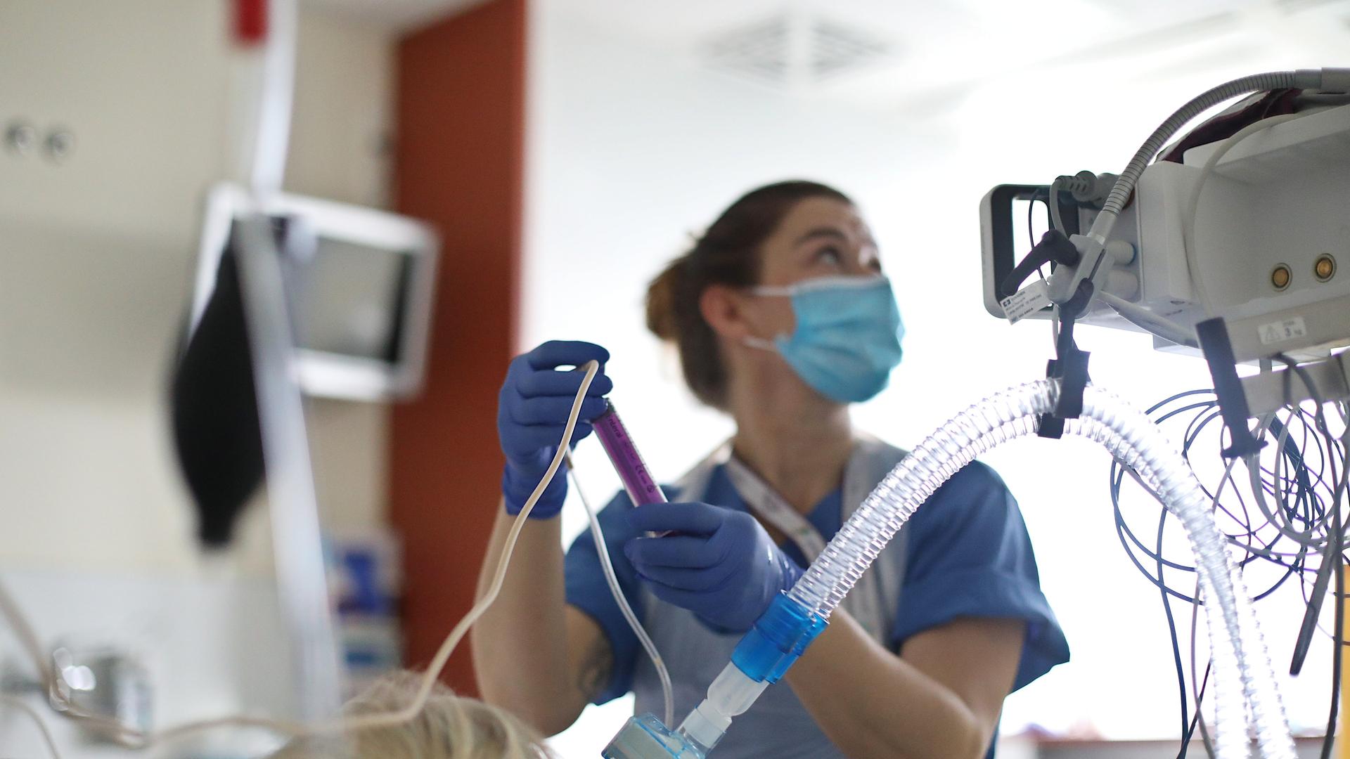 das Bild zeigt eine Intensiv-Krankenpflegerin bei der Arbeit in einem Raum mit modernen medizinischen Gerätschaften.