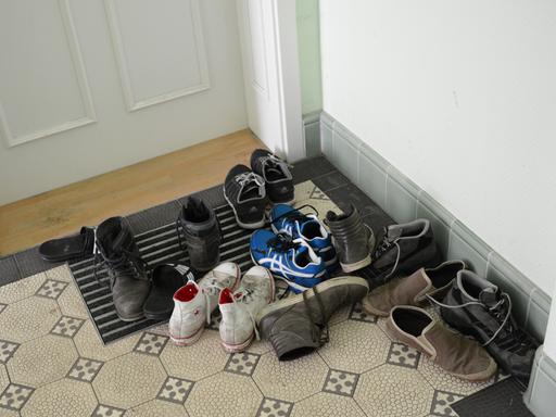 Straßenschuhe stehen vor einer Haustür in einem Wohnhaus. 
