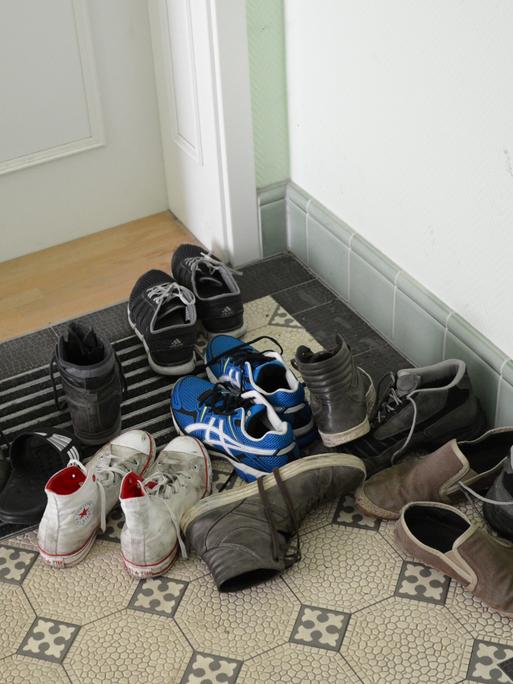 Straßenschuhe stehen vor einer Haustür in einem Wohnhaus. 