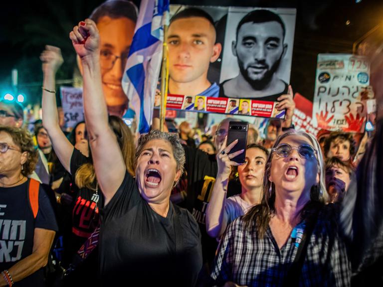 Israelische Demonstranten gestikulieren, skandieren und halten ein Plakat mit der israelischen Geisel Matan Angrest während einer Demonstration hoch. 