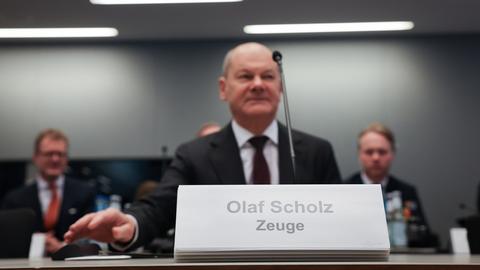 Ein Mann sitzt an einem Tisch. Vor ihm ist ein Schild. Darauf steht: "Olaf Scholz. Zeuge". Es ist Bundeskanzler Olaf Scholz (SPD) bei einer Sitzung des Parlamentarischen Untersuchungsausschusses "Cum-Ex".