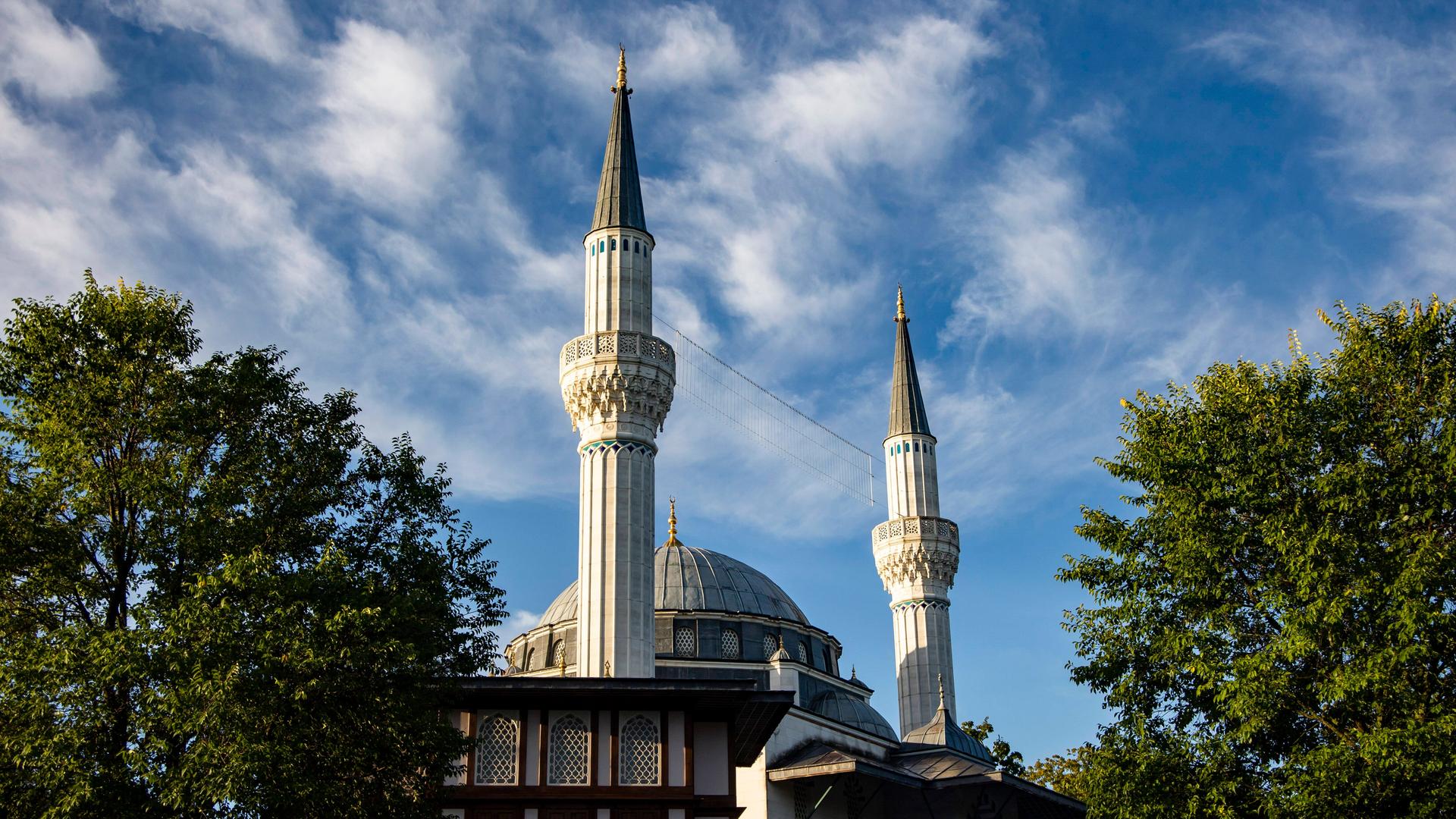 Aussenansicht einer Moschee mit zwei Türmen, umrahmt von Bäumen.