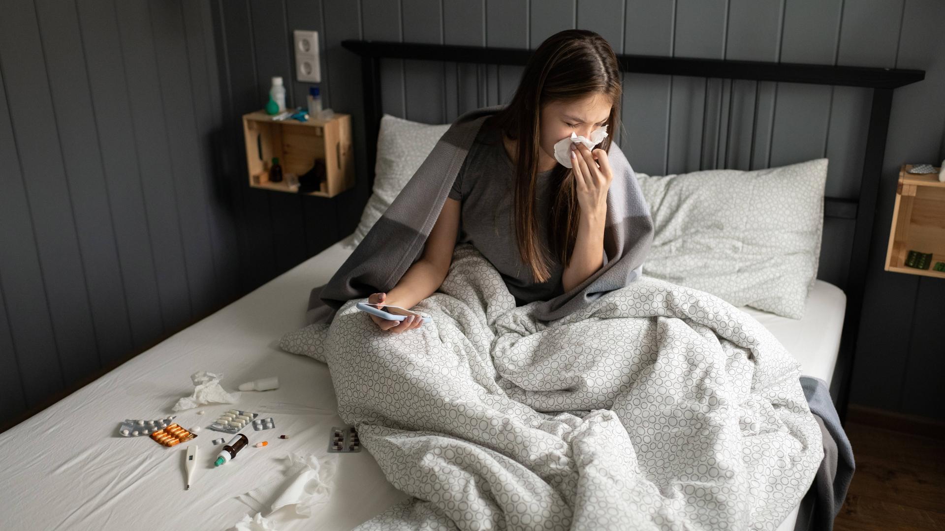 Eine Frau sitzt krank im Bett. Eine Frau sitzt krank im Bett.