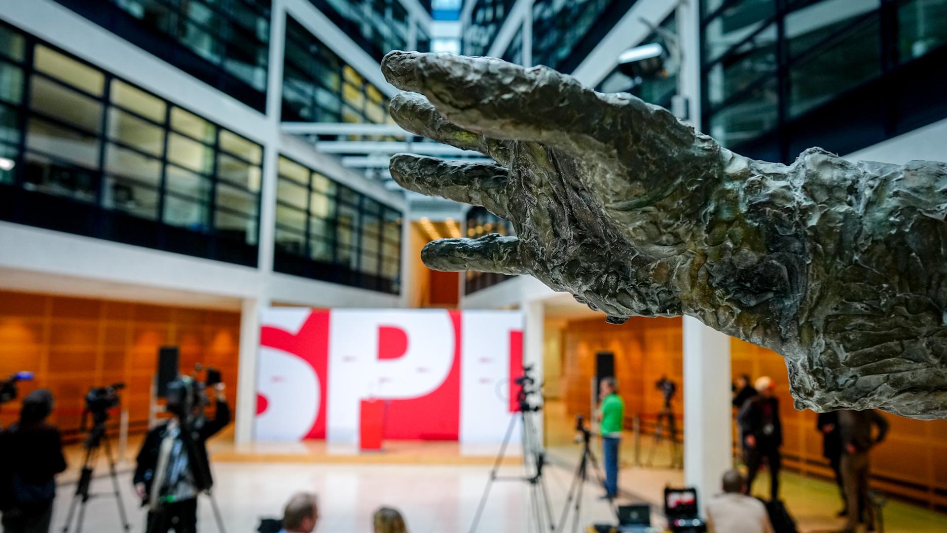 Die bronzene Hand der Willy-Brandt-Statue ist im Atrium in der SPD-Parteizentrale, dem Willy-Brandt-Haus vor dem Parteilogo zu sehen. Die bronzene Hand der Willy-Brandt-Statue ist im Atrium in der SPD-Parteizentrale, dem Willy-Brandt-Haus vor dem Parteilogo zu sehen.