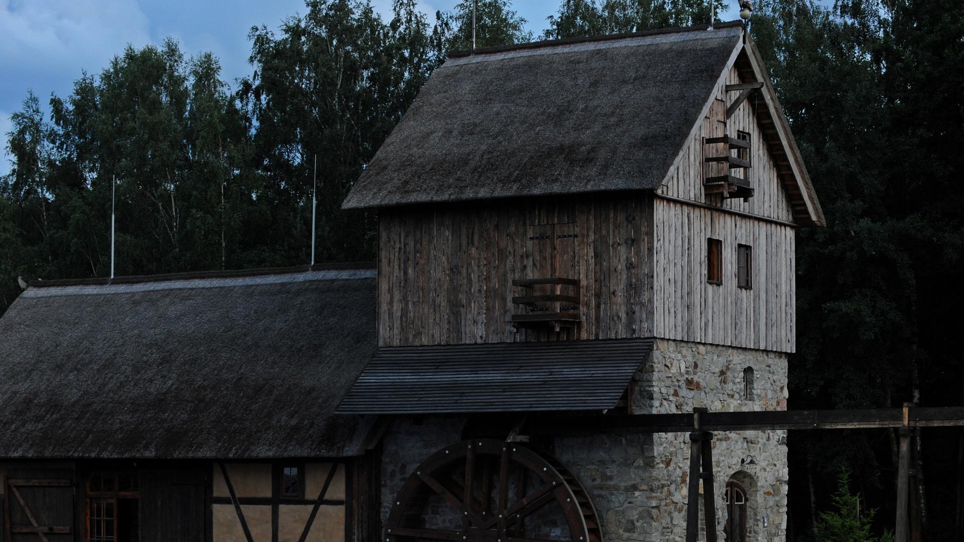 Aufnahme der Schwarzen Mühle in der Lausitz bei Dämmerlicht. Das Mühlhaus ist aus Stein und Holz gebaut, an der Seite hängt ein Mühlrad.