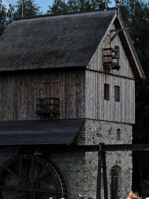 Aufnahme der Schwarzen Mühle in der Lausitz bei Dämmerlicht. Das Mühlhaus ist aus Stein und Holz gebaut, an der Seite hängt ein Mühlrad.