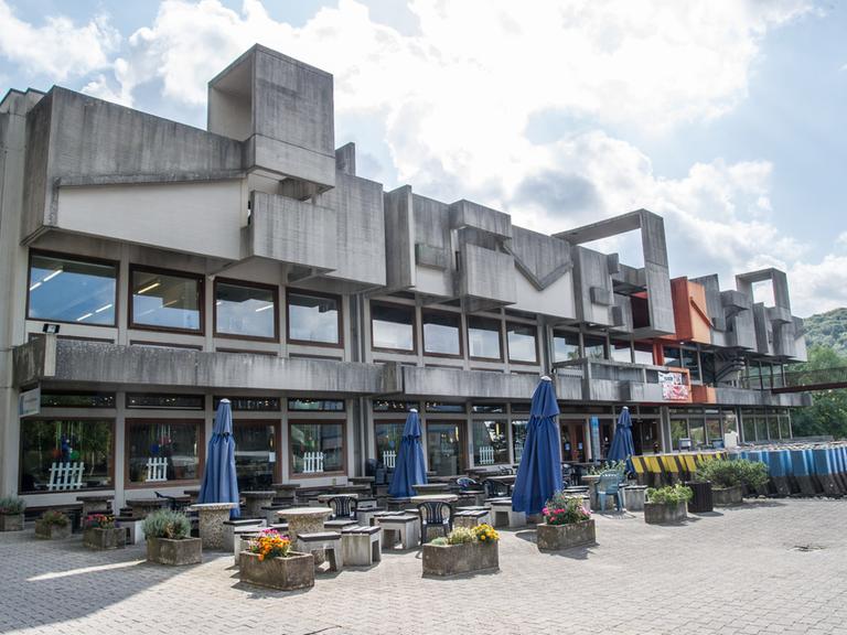 Die Mensa der Universität des Saarlandes in Saarbrücken. Der Betonbau wirkt trotz Blumenkästen und farblicher Akzente gewaltig. 