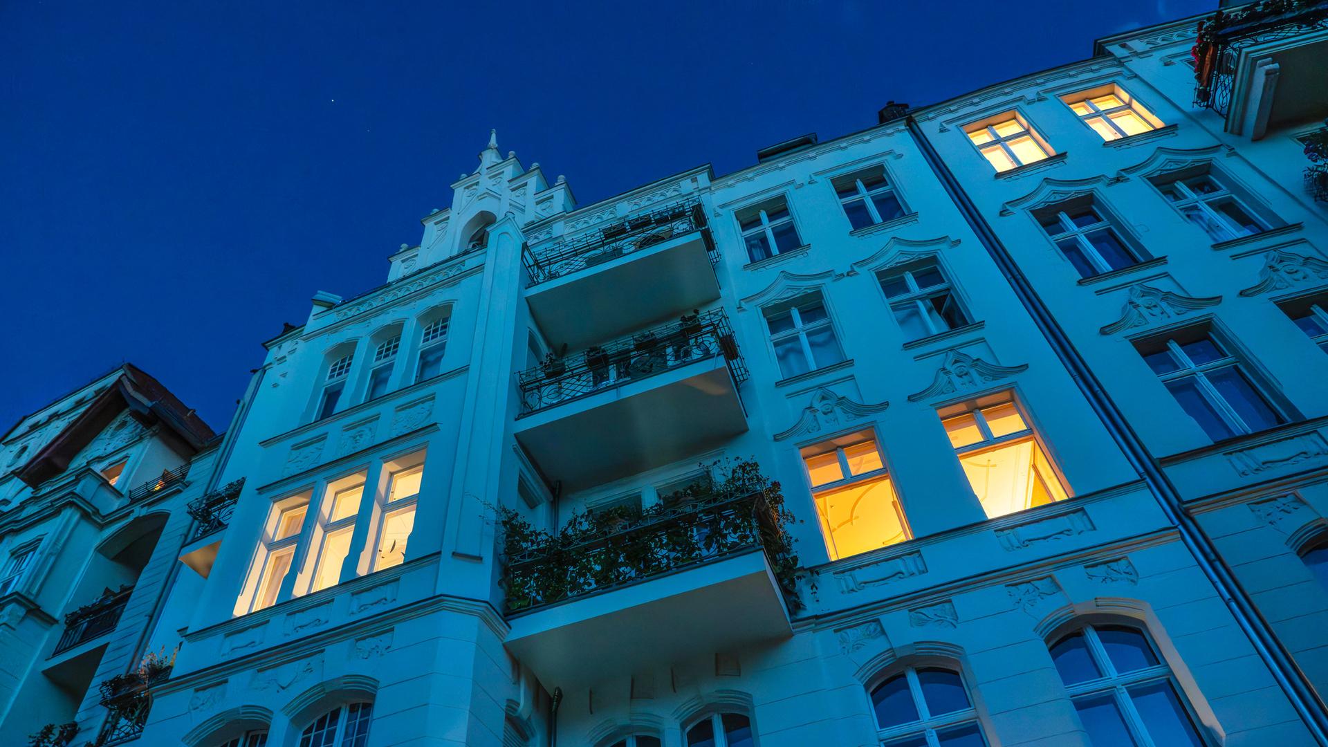 Erleuchtete Fenster an einer Altbaufassade am Landwehrkanal, abends in Berlin.