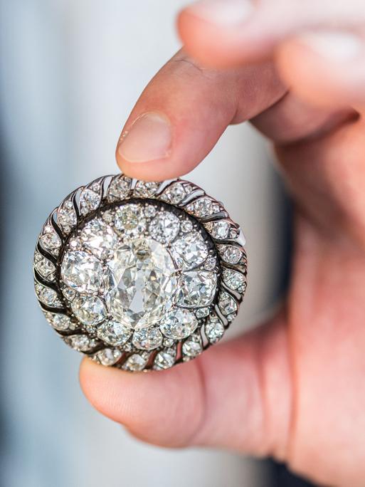 Ein Mitarbeiter des Auktionshauses Sotheby’s hält die Brosche mit alten Diamanten im Minenschliff in den Händen. Sie gehörte einst Napoleon Bonaparte und wurde von der preußischen Armee beschlagnahmt.