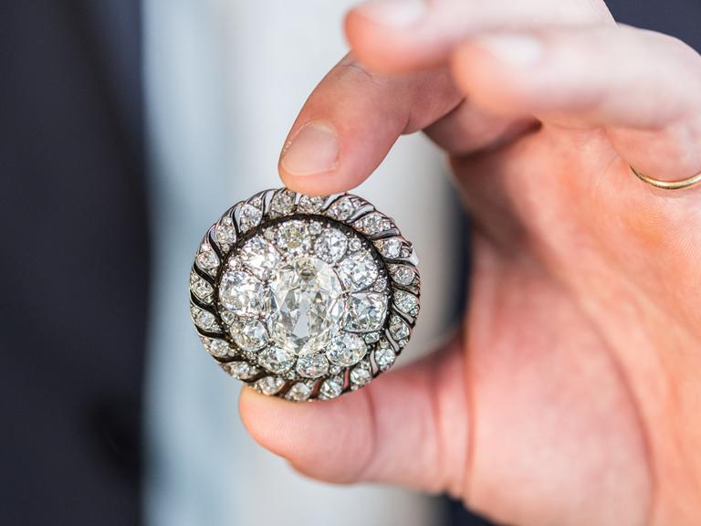 Ein Mitarbeiter des Auktionshauses Sotheby’s hält die Brosche mit alten Diamanten im Minenschliff in den Händen. Sie gehörte einst Napoleon Bonaparte und wurde von der preußischen Armee beschlagnahmt.