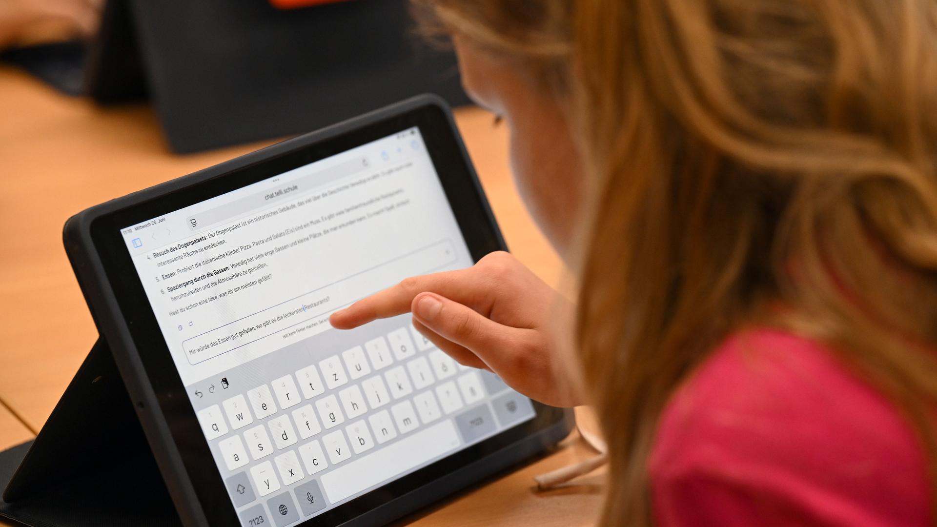 Eine Schülerin sitzt an einem Tablet und arbeitet mit dem KI-Chatbot "Telli". Eine Schülerin sitzt an einem Tablet und arbeitet mit dem KI-Chatbot "Telli".