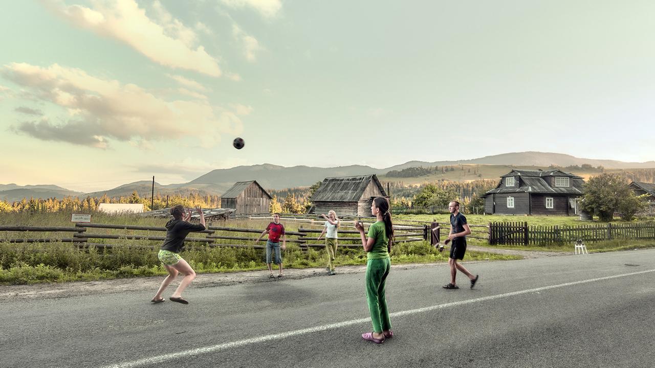 Jugendliche spielen auf einer Dorfstraße mit einem Ball.