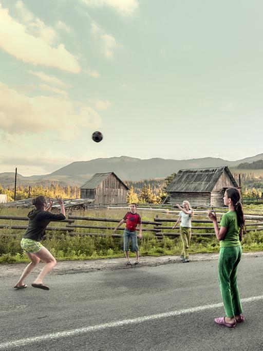 Jugendliche spielen auf einer Dorfstraße mit einem Ball.