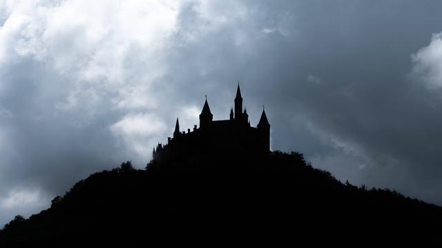 Die dunkle Silhouette einer Burg ist vor einer Wolkendecke zu sehen. 