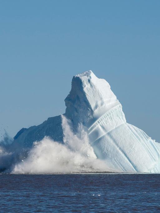 Eismassen vor einer Bucht in Grönland brechen von einem enormen Eisberg ab