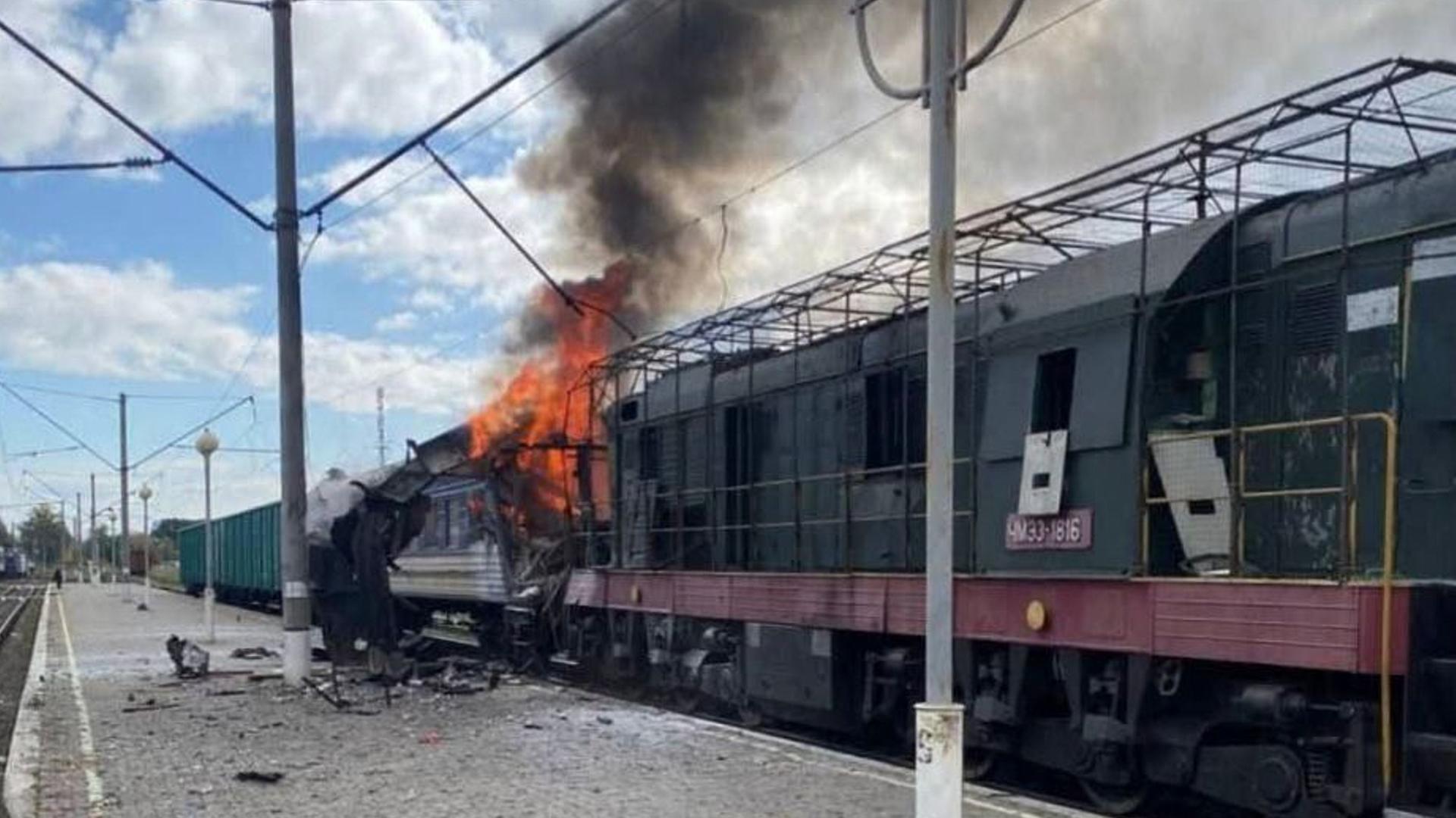 Es ist Tag. Der Zug steht an einem Bahngleis, ein Abteil brennt. Auf dem Bahngleis liegen Trümmer. Schwarzer Rauch steigt in den blauen bewölkten Himmel. 