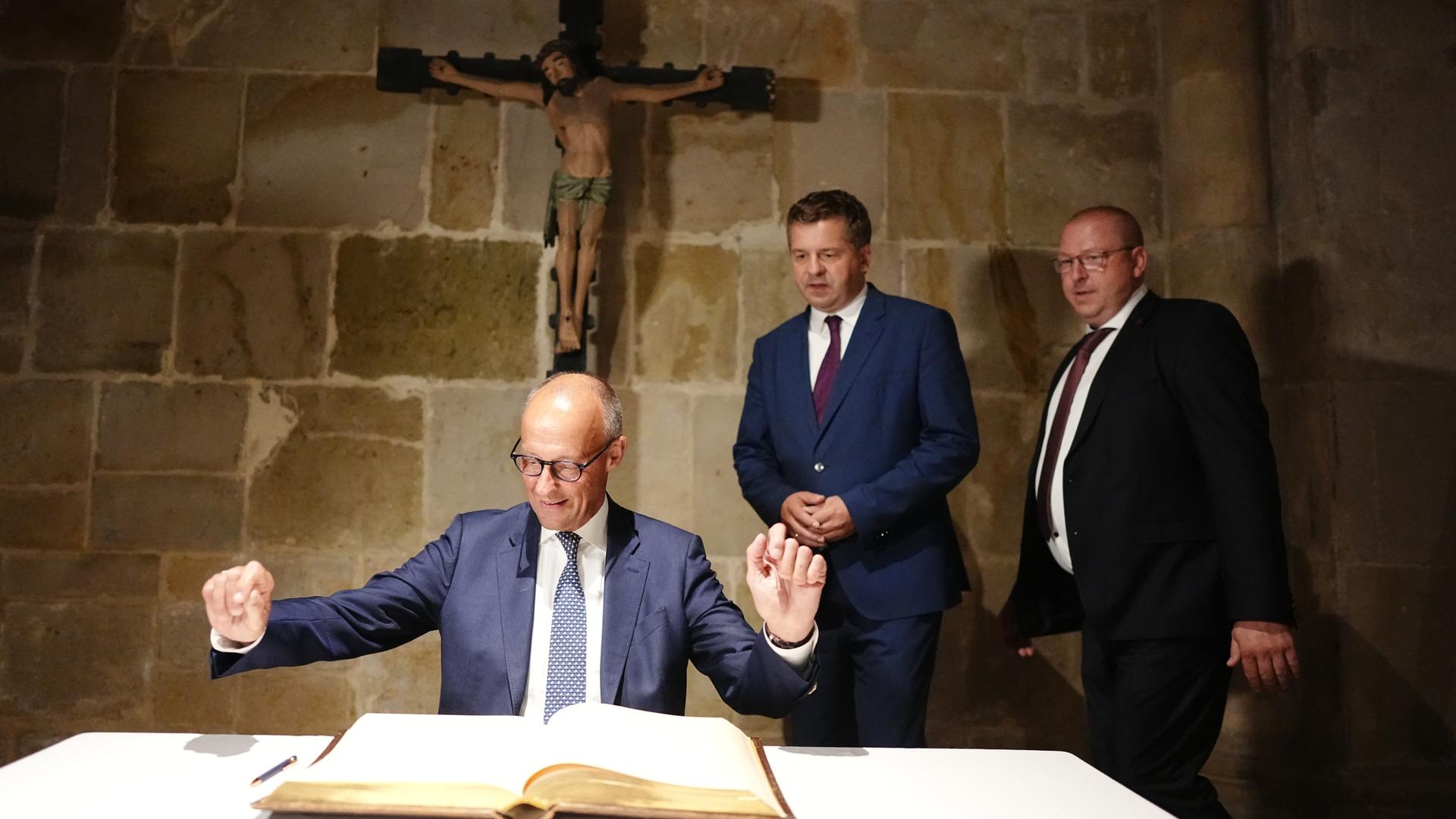 Bundeskanzler Friedrich Merz breitet die Arme aus. Vor ihm liegt das Goldene Buch der Stadt Quedlinburg, direkt hinter ihm an der Wand prangt ein großes Kruzifix. Daneben steht der Spitzenkandidat der CDU-Sachsen-Anhalt, Sven Schulze. Bundeskanzler Friedrich Merz breitet die Arme aus. Vor ihm liegt das Goldene Buch der Stadt Quedlinburg, direkt hinter ihm an der Wand prangt ein großes Kruzifix. Daneben steht der Spitzenkandidat der CDU-Sachsen-Anhalt, Sven Schulze.