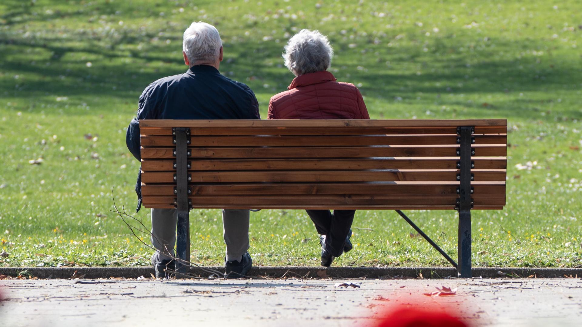 Ein älteres Seniorenpaar sitzt auf einer Bank in einem Park.