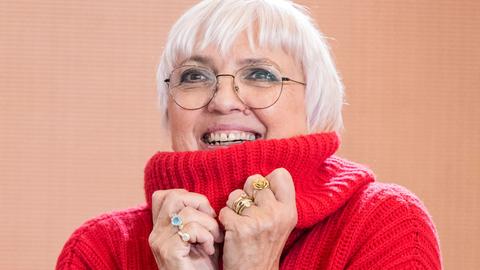 Porträt der Kulturstaatsministerin Claudia Roth, sie trägt einen roten Rollkragenpullover und lacht.