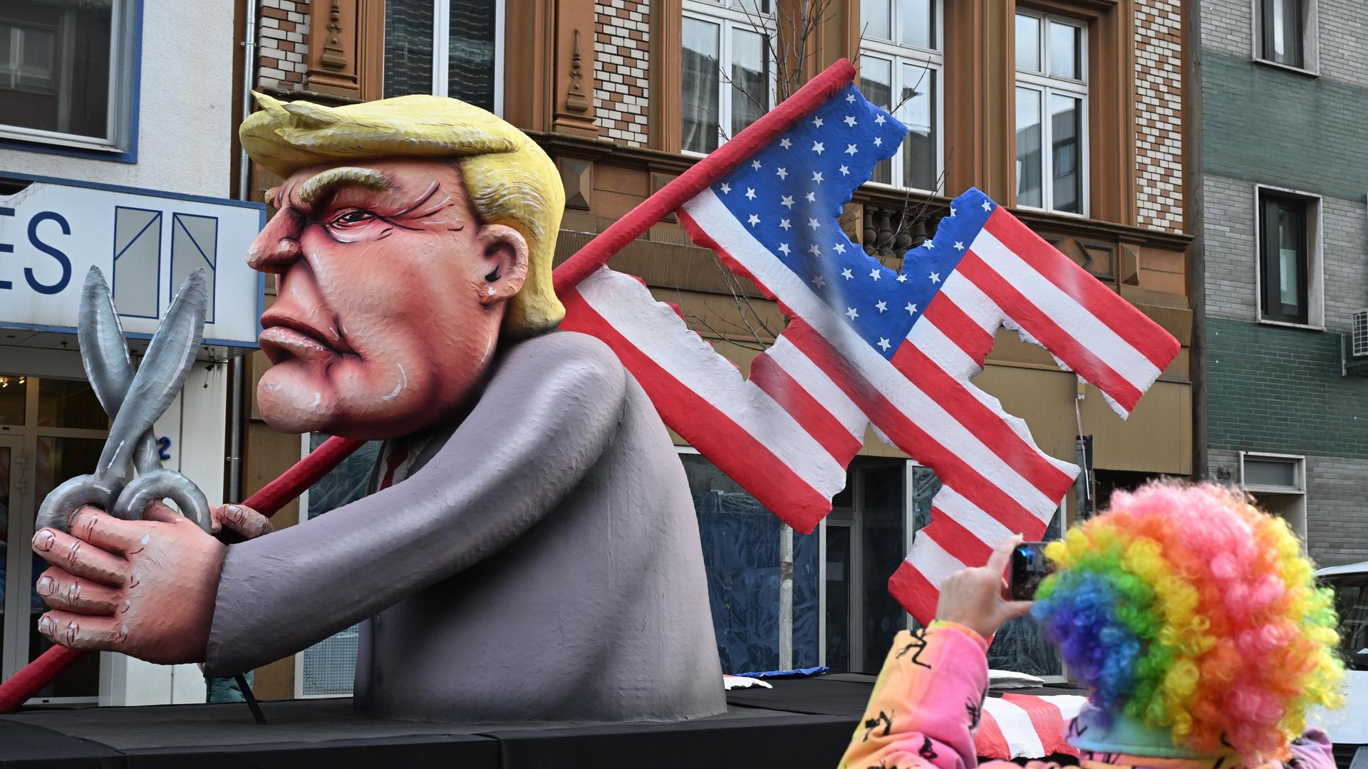 Der Mottowagen, der den designierten US-Präsidentschaftskandidaten Trump mit der US-Nationalflagge in Form eines Hakenkreuzes zeigt und mit einer Schere in der Hand, fährt im Rosenmontagszug.