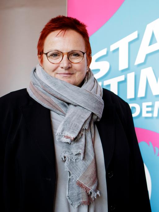 Elke Ferner steht vor einem Schild mit der Aufschrift "Starke Stimmen für die Demokratie"