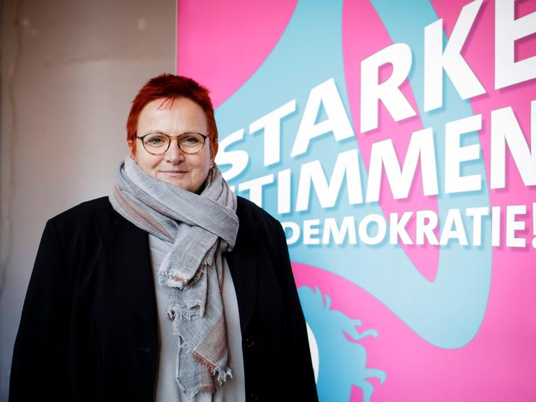 Elke Ferner steht vor einem Schild mit der Aufschrift "Starke Stimmen für die Demokratie"