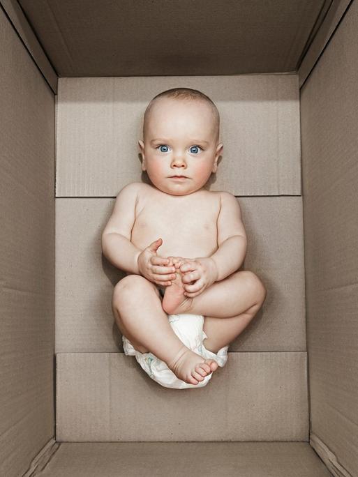 Ein kleines Baby liegt in einer Pappbox.