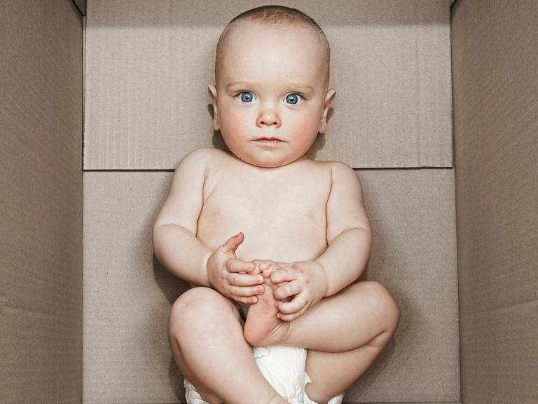 Ein kleines Baby liegt in einer Pappbox.