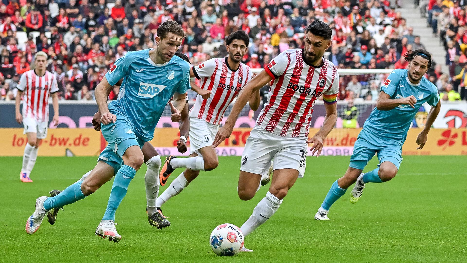 Mehre Spieler beider Mannschaften laufen dem Ball hinterher.