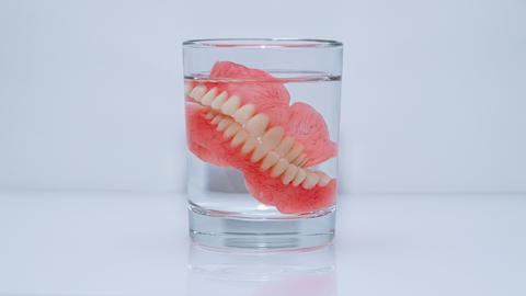 Eine Zahnprothese liegt in einem Wasserglas.