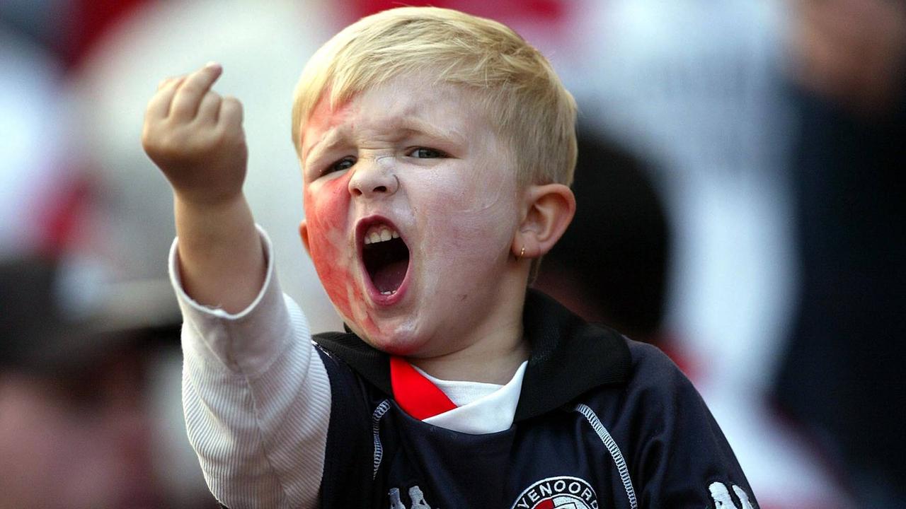 Ein kleiner Junge im Fußballtrikot schreit und zeigt am Spielfeldrand der gegnerischen Mannschaft den Mittelfinger. 