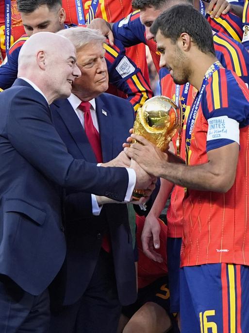 US-Präsident Donald Trump (Mitte) und FIFA-Präsident Gianni Infantino (links) überreichen Rodri (rechts), dem Kapitän der Spanier, nach dem 1:0-Sieg über Argentinien im New Jersey Stadium in East Rutherford, New Jersey, den goldenen Siegerpokal. US-Präsident Donald Trump (Mitte) und FIFA-Präsident Gianni Infantino (links) überreichen Rodri (rechts), dem Kapitän der Spanier, nach dem 1:0-Sieg über Argentinien im New Jersey Stadium in East Rutherford, New Jersey, den goldenen Siegerpokal.