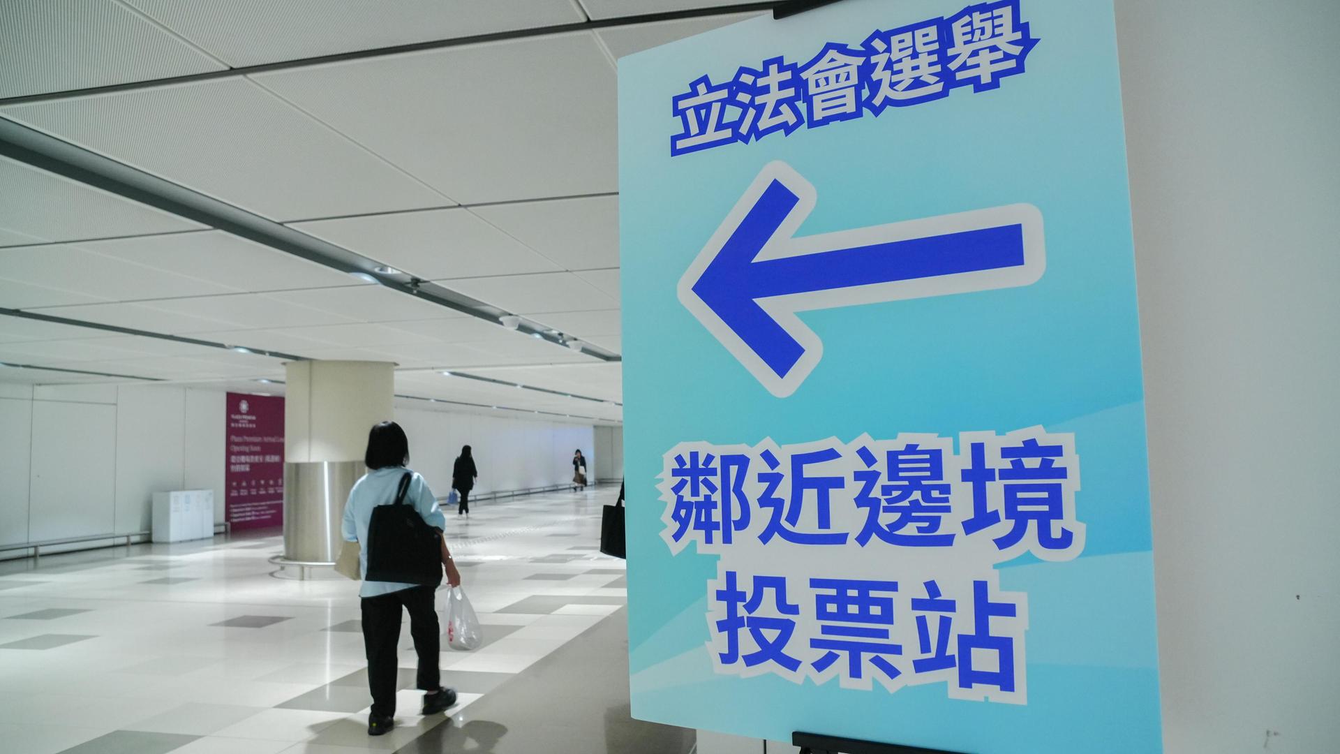 Schild und einige Personen in einem Hongkonger Wahllokal