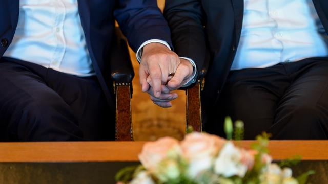Das Foto zeigt die Hände von zwei Männern, die gerade heiraten.