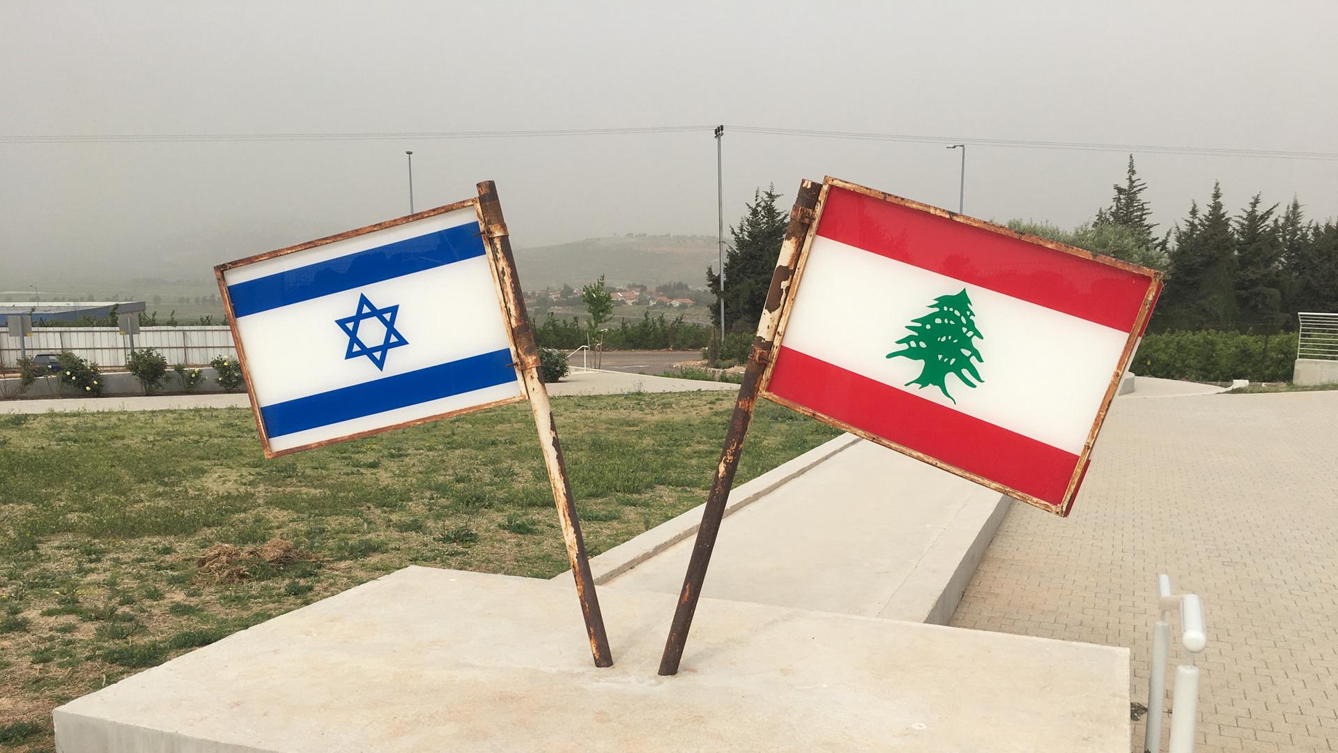 Eine israelische und eine libanesische Fahne stehen auf einer Steinplatte.